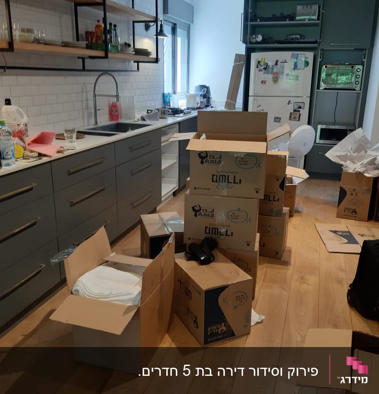 ארגזים פתוחים במטבח עם כלים וחפצים לאריזה